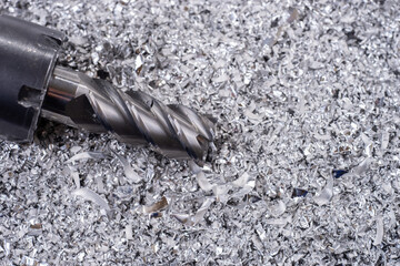 Silver end mill cutter with metal shavings. Processing of ferrous metals in a factory