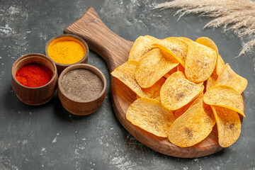 Side view of tasty potato chips spices with ketchup on gray background