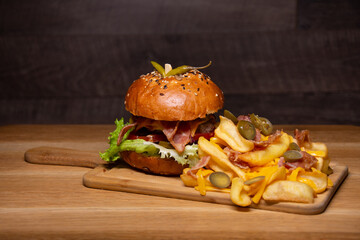 Tasty hamburger with french fries on wooden table