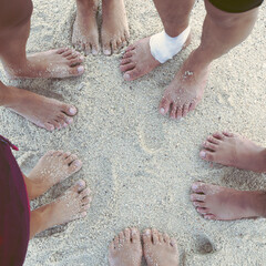 Top view image of feet of young people standing someone uses Insurance during the trip. some friends have Bandages on the feet standing Sore feet on sandy beach. Concept Insurance.