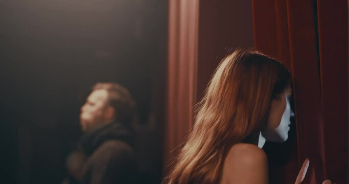 Nervous actress peeking through curtains before performance