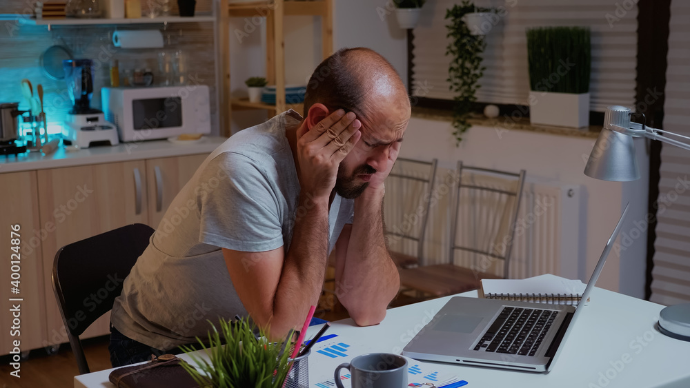 Poster concentrated man with headache trying to finish a project for work during midnight. busy focused emp