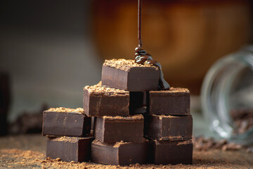 Heap of delicious cubes of bitter dark chocolate sprinkled with cocoa powder and poured with liquid...