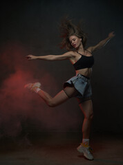 Fototapeta na wymiar Caucasian beautiful woman with long brown hairs jumps dancing in dark smokey background.