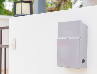 Modern metal mailbox on white concrete wall with modern home in the background