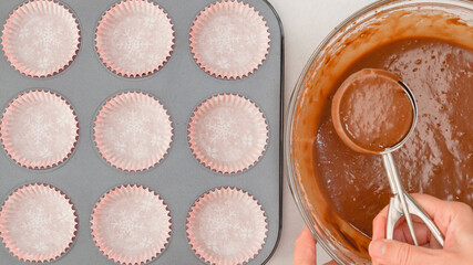 Chocolate muffins recipe. Pouring chocolate batter into lined cupcake pan using an ice cream scoop....