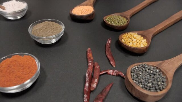 Sabut Urad(black)  Chana(yellow)  Moong(green)  Masoor(red) pulses kept with spices. Famous Indian dals things with wooden spoons for measurement against a dark background