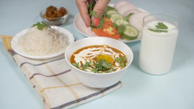 Fresh coriander leaves sprinkled to garnish Dal Makhani - famous Indian dish. Dal Makhani - Indian lunch/dinner meal served with plain steamed rice  salad  pickle/Achaar  and buttermilk/Chaas/curd ...