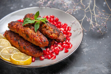 front view long meat cutlets with lemon and pomegranates on a grey background meal roll dish