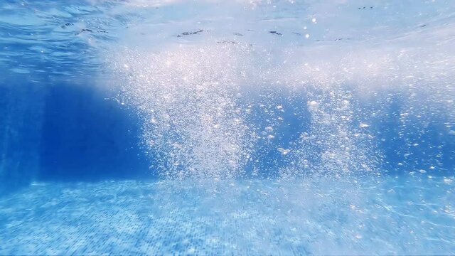 Underwater view of Bubbles from a Scuba diver ascending to the surface of the swimming pool, slow motion