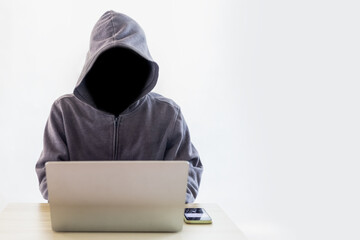 Hacker black face anonymous with laptop white background, copy space.
