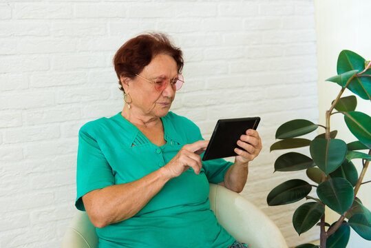 Elderly woman is learning to interact with tinternet using tablet computer