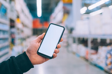 Mock-up technology. The guy holds a smartphone in his hands on the background supermarket.