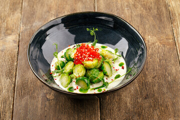Brussels sprouts with caviar with creamy sauce in a black bowl