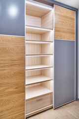 Stylish large wardrobe with LED lighting, sliding doors, shelves and inner drawer made of light laminated boards in contemporary interior designer lobby