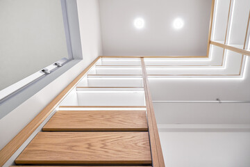 Elegant white shelving with LED lighting. Shelving of laminated boards with edges and faces of drawers made of oak veneer plywood sheets in walk-in closet. Directly below