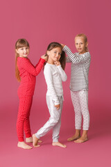 Fototapeta premium Cute girls making braids on color background