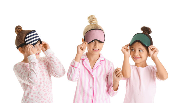 Cute little girls in pajamas and sleep masks on white background