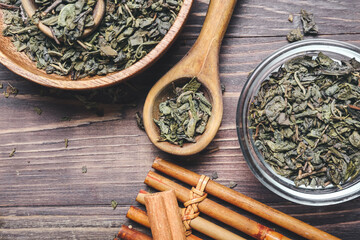 Bowls and spoon with dry green tea on wooden background