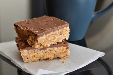 Chocolate caramel rice crispy treats on parchment paper with copy space on the right side. 