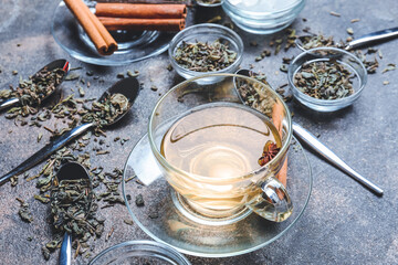 Composition with cup of green tea, cinnamon and dry leaves on grunge background