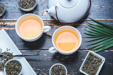 Composition with cups of green tea, teapot and dry leaves on wooden background