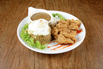 a plate of fried rice with chicken chop and fried egg