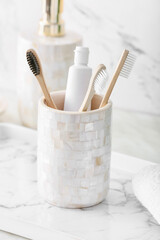 Fototapeta na wymiar Holder with wooden toothbrushes and toothpaste on table in bathroom