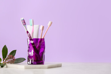 Holder with toothbrushes and toothpaste on table