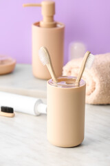 Holder with wooden toothbrushes on table in bathroom
