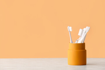 Holder with toothbrushes and toothpaste on table