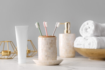 Holder with toothbrushes and toothpaste on table in bathroom