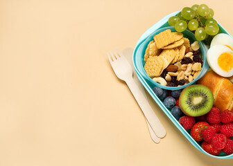 School lunch box with sandwiches, vegetables and fruits on orange background.