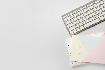 Computer keyboard and notebooks on white background
