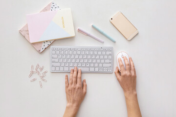 Obraz premium Female hands with computer keyboard, stationery and mobile phone on white background