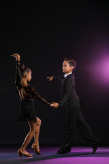 Cute little children dancing against dark background