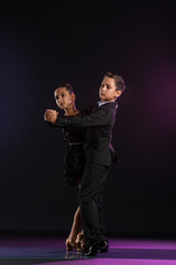 Cute little children dancing against dark background