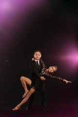 Cute little children dancing against dark background