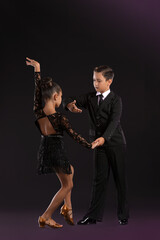 Cute little children dancing against dark background