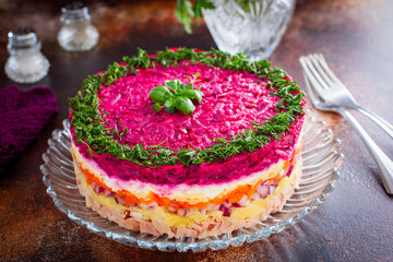 Festive bright salad with beets and chicken on a glass dish, decorated with fresh herbs, horizontal