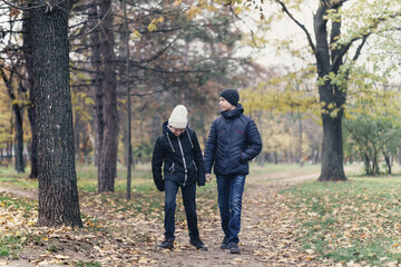 Fototapeta premium teen girl and boy walking through the park and enjoys autumn, beautiful nature with yellow leaves