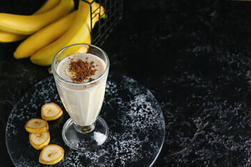 Glass of tasty banana smoothie on dark background