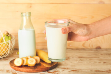 Female hand with glass of tasty banana smoothie