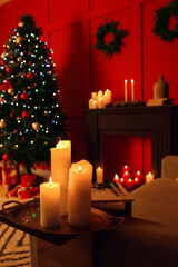 Burning candles in living room decorated for Christmas