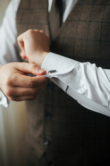 the man fastens his cufflinks.Men's suit. Business suit. Groom.Wedding fashion.