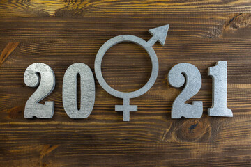 Silver symbol of gender equality between the numbers 2021 on a wooden background