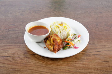 Malay traditional food called "Nasi Minyak" with colorful rice red chili spicy sauce chicken cucumber carrot and potato on the white dish.
