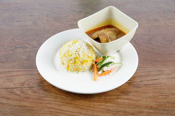 Malay traditional food called "Nasi Minyak" with colorful rice with chicken curry cucumber carrot and potato on the white dish.
