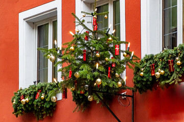 Christmas tree hanging in front of white windows on a red house wall in medieval town of Rothenburg ob der Tauber, Bavaria, Germany