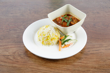 Malay traditional food called "Nasi Minyak" with colorful rice red chili spicy sauce chicken cucumber carrot and potato on the white dish.